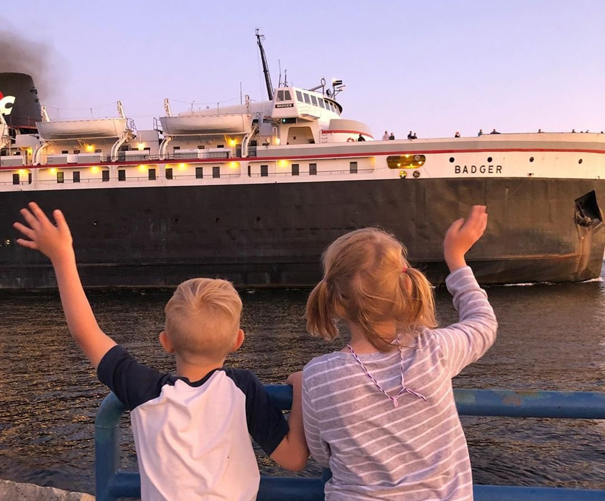 273149502_10158202531831561_7575574332926077721_n_2 a little boy standing in front of a boat
