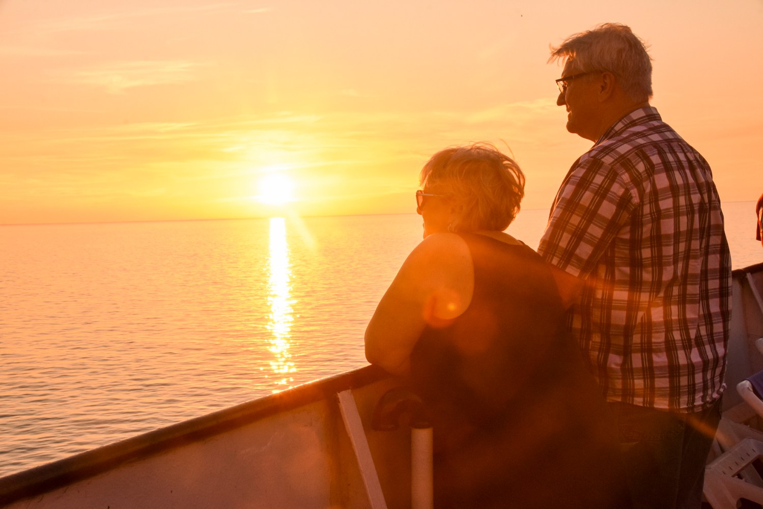 A couple looks out onto the horizon of a beautiful sunset.