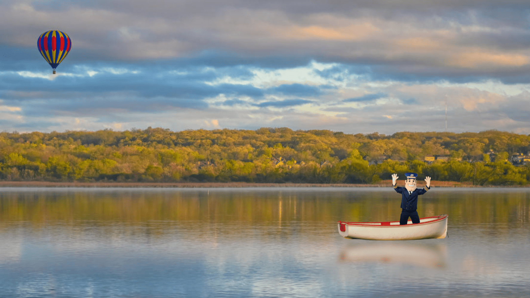 Cartoon sailor standing in a small boat on a lake, with a colorful hot air balloon in the sky.