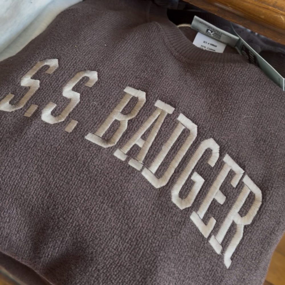Brown sweatshirt with 'S.S. BADGER' text in white, folded in a drawer.