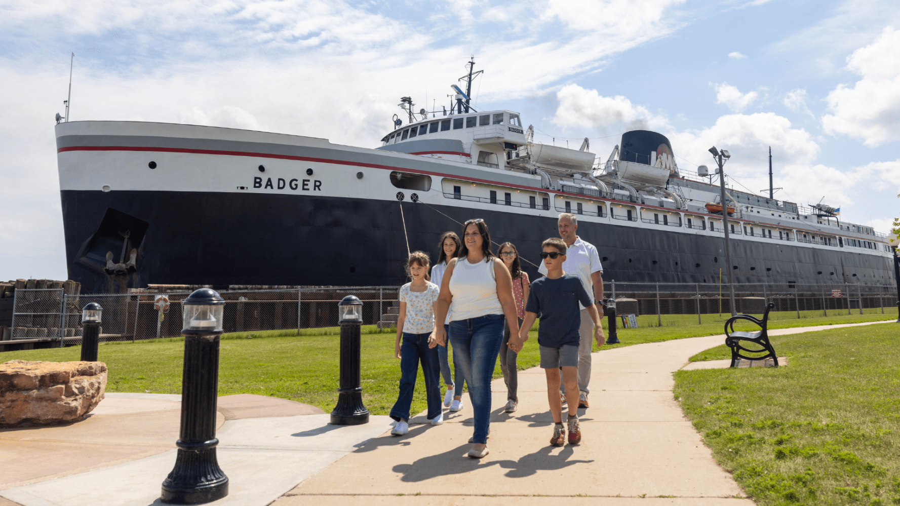 Family walking near a large ship named Badger at a harbor.