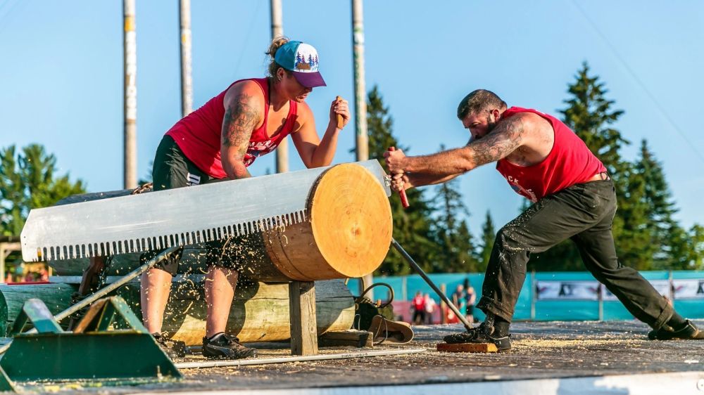 Two people sawing a large log in a competitive setting.
