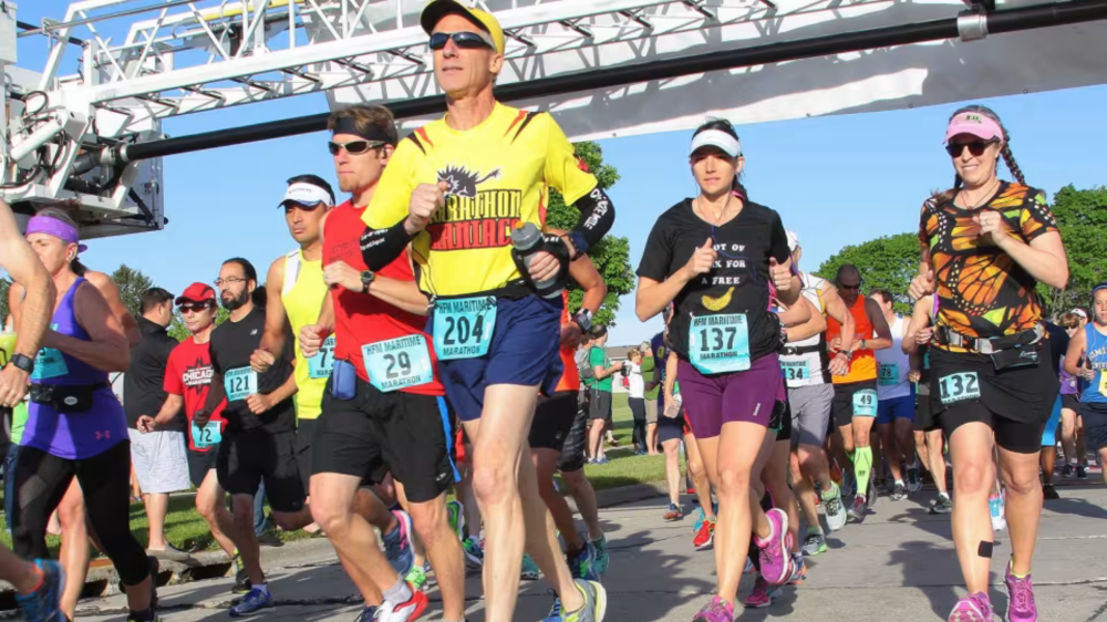 Group of runners in a marathon wearing colorful outfits and race numbers.