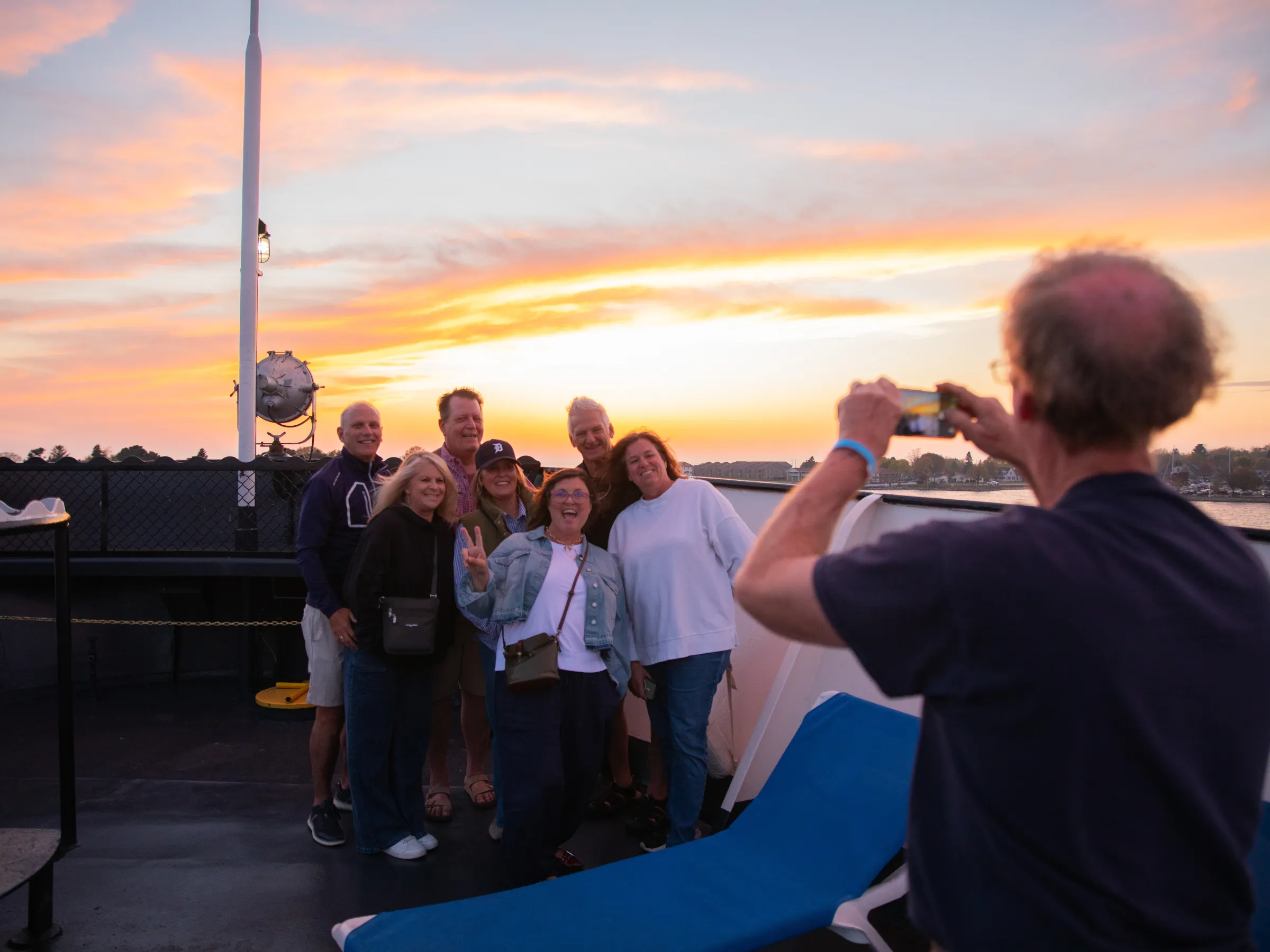 Group poses for a photo on a boat at sunset.