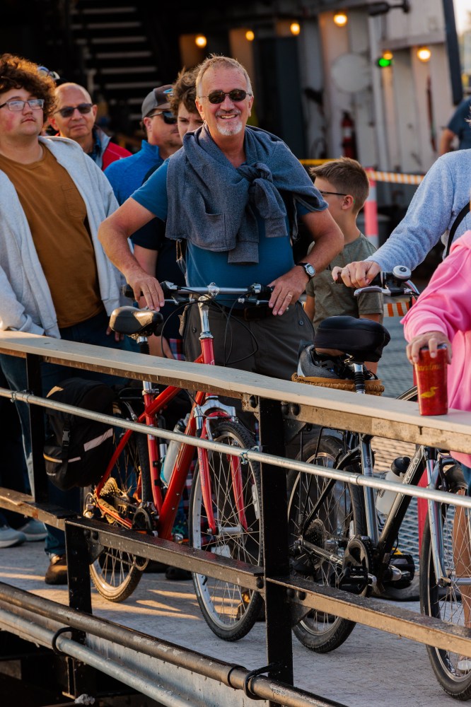 People with bicycles on a pier, smiling and enjoying the sunny day.